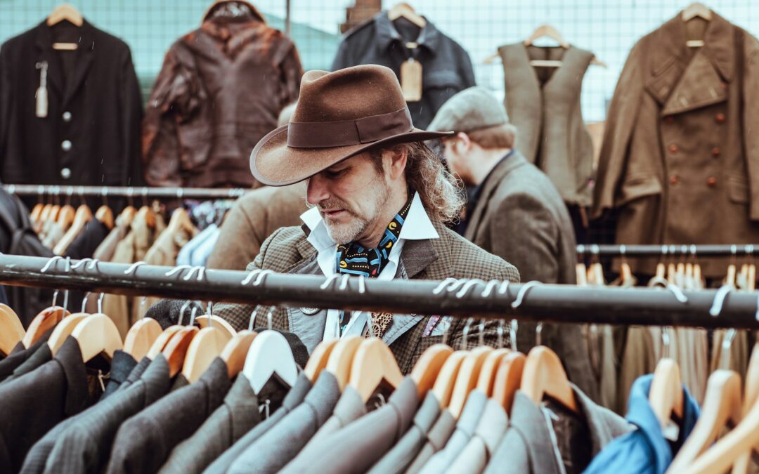 man in brown cowboy hat in front of hanged suit jackets