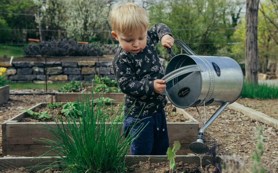 boy in black and white long sleeve shirt standing beside gray metal watering can during daytime