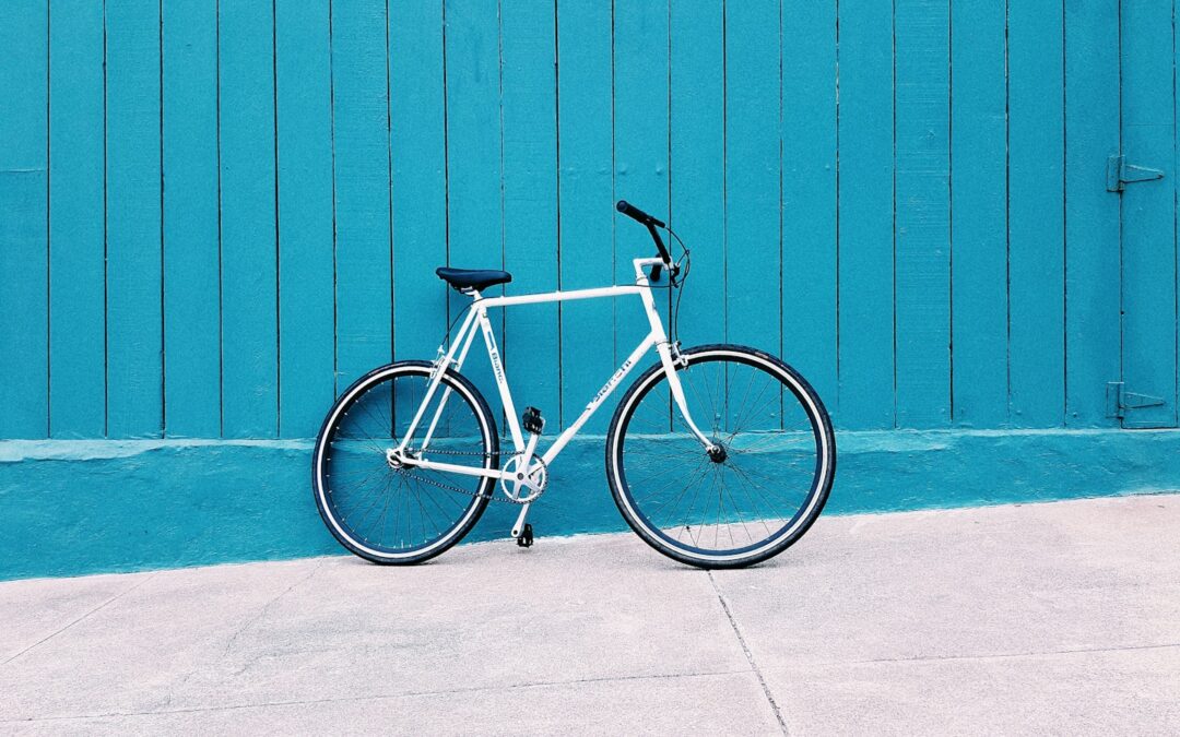 white road bike leaning on teal wooden wall during daytime